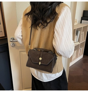 Detail of dark brown vintage satchel with contrast stitching and golden clasp on model