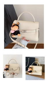Close-up of beige lychee grain leather handbag with dog plush charm and metal lock