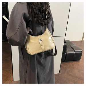 Detail of beige faux leather underarm bag with silver buckle worn by a model