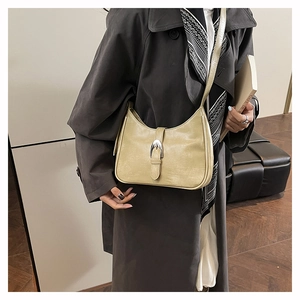 Close-up of a light green leather shoulder bag featuring a silver metal buckle and strap