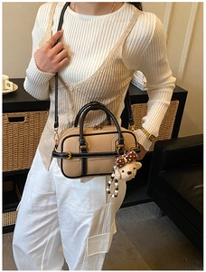 Détail du sac à main en cuir grainé beige avec garniture dorée et breloque ours
