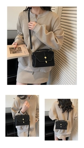 Detail of black crossbody square bag with white stitching and golden circular clasp