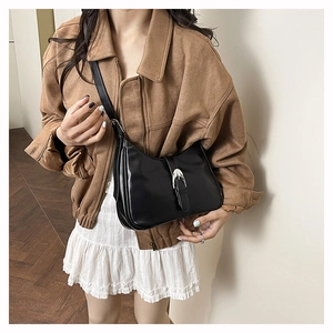 Detailed view of black leather crossbody bag with silver horseshoe buckle and adjustable strap