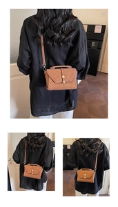 Detail view of caramel brown vintage leather handbag with round metal lock and top handle