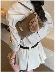 Brown lychee leather crossbody bag detail with golden hardware and plush bear charm decor