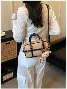 Vue arrière du sac baguette beige avec bordure en cuir noir et breloque petit ours