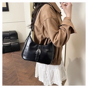 Detail of minimalist black faux leather underarm bag with silver buckle and sleek texture