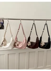 Detail view of four colorful crescent shoulder bags with plush lamb charms on display