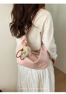 Detailed side view of a pink minimalist hobo bag with a cute plush doll accessory