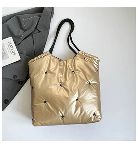 Detail of gold quilted tote bag with black star embroidery and rope straps