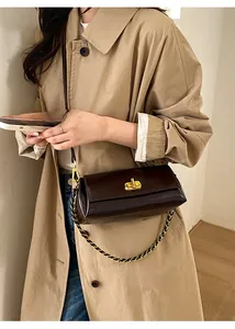 Detail of a dark brown glossy leather shoulder bag with gold twist lock and chain strap