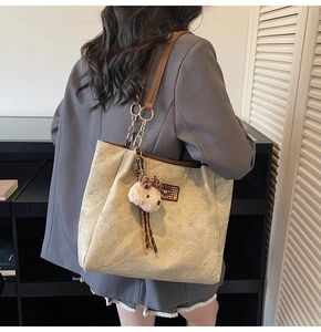 Détail du sac cabas beige à motifs d'ours, bandoulière en cuir et chaîne et charme ours