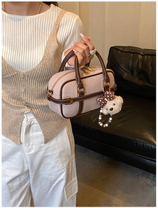 Détail du sac baguette rose clair avec bordure marron et breloque ours en peluche