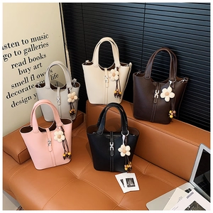 Detailed close-up of textured leather bucket bags in multiple colors with floral charms