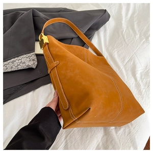 Close-up of caramel tote bag with white stitching and gold metal buckle detail