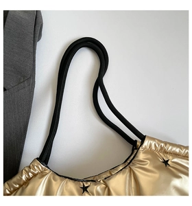 Detail of metallic gold tote bag with black embroidered stars and rope handles