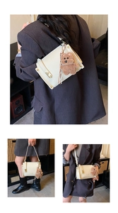 Detail of cream-colored crossbody bag with gold buckle and cute brown bear keychain charm