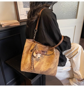 Détail d'un sac cabas marron vintage avec motifs gravés et charmant pendentif d'ours