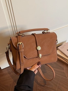 Vintage brown leather crossbody bag with top handle and elegant round metal buckle