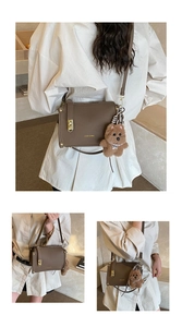 Detail of coffee-colored textured leather handbag with gold buckle and cute bear charm