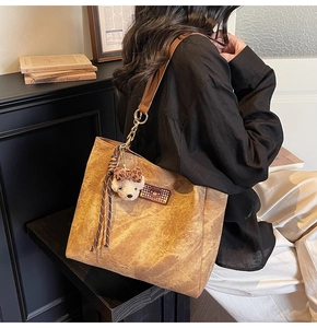 Détail du sac cabas marron vintage avec broderie ours et charm peluche sur l'épaule