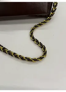 Close-up of a dark brown leather handbag featuring a golden turn-lock and chain strap