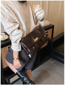 Detail view of coffee brown quilted tote with gold chain strap and metal twist-lock