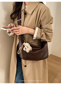 Deep brown minimalist hobo bag with cute teddy bear charm on stylish trench coat model