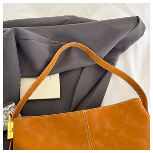 Detail of caramel tote bag with white contrast stitching and gold metal buckle