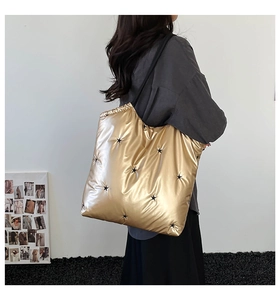 Detail of gold quilted tote bag featuring black star embroidery and metallic finish