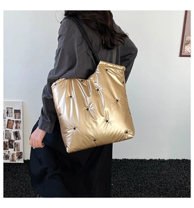 Detail of large gold puffer tote bag with black star embroidery and quilted texture