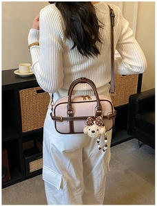 Détail du sac en cuir rose avec poignées marron et adorable breloque ours