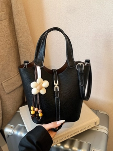 Black pebbled leather bucket bag with white contrast stitching and a floral bag charm
