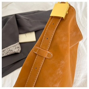 Close-up of caramel leather tote bag with gold buckle and contrast white stitching