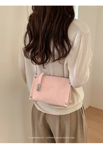 Pink square shoulder bag with silver studs and metal buckle worn by a model from behind