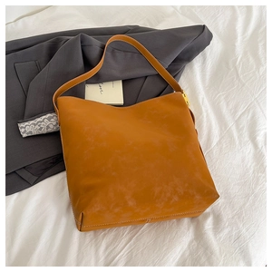 Detail of brown leather tote bag with white stitching on casual blazer background