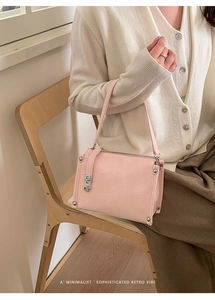 Detail of light pink baguette bag with glossy texture and silver metal buckle on model