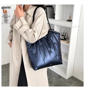 Detail of navy quilted down tote bag with blue star embroidery and black straps