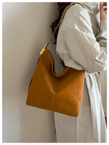 Detail of tan suede tote bag featuring white stitching and gold metal strap buckle