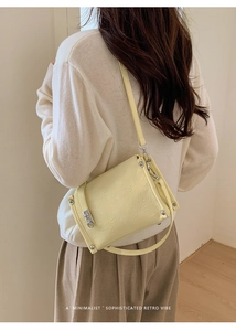 Close-up of yellow baguette bag with pleated texture and silver rivets on a model