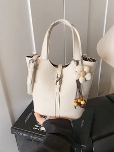 Chic cream leather bucket bag with silver H-buckle and floral charm accessory