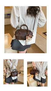 Détail du mini sac polochon marron foncé avec texture grainée et pendentif ours