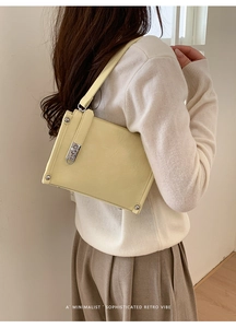 Close-up of cream square leather bag with silver buckle and rivets on a model