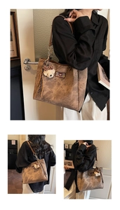 Detail of a brown tote bag featuring textured faux leather, plush bear charm and tassels