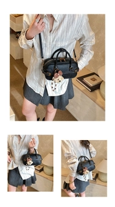 Détails du sac baguette en cuir grainé noir avec finitions dorées et breloque ourson