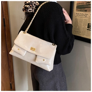 Detail view of cream quilted tote bag with gold chain and glossy faux leather texture