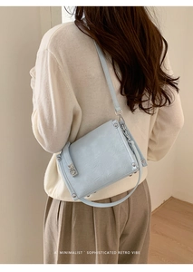 Detail showing light blue square bag with pleated leather texture and silver buckle