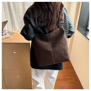 Deep brown tote bag detail with white contrast stitching and soft matte leather texture