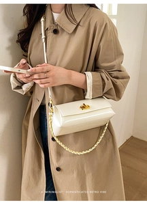 Close-up of beige leather square bag with gold twist lock and woven metal chain detail