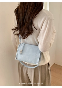 Detail of light blue pleated leather shoulder bag with silver metallic clasp on model